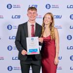 This photo depicts a student with their award against the LCBU photo wall.
