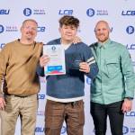 This photo depicts a student with their award against the LCBU photo wall.