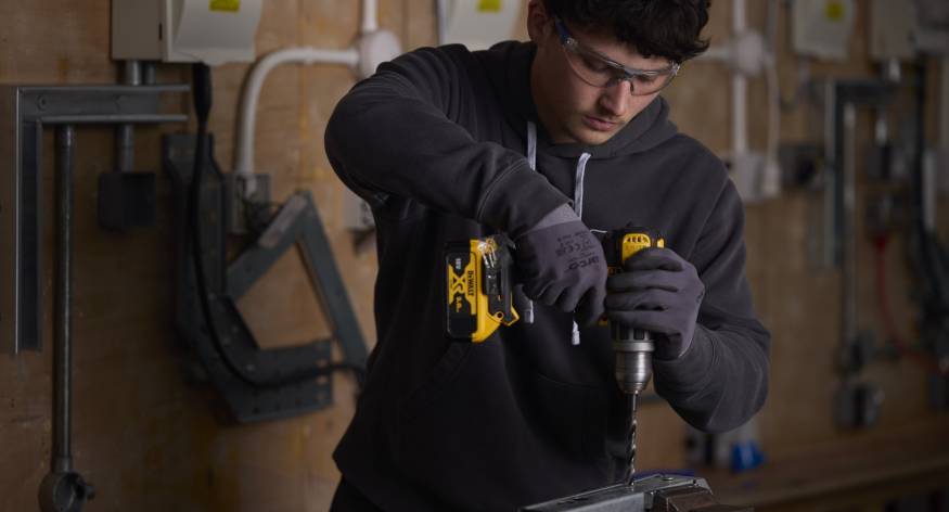 This image depicts an LCB student using a power drill.